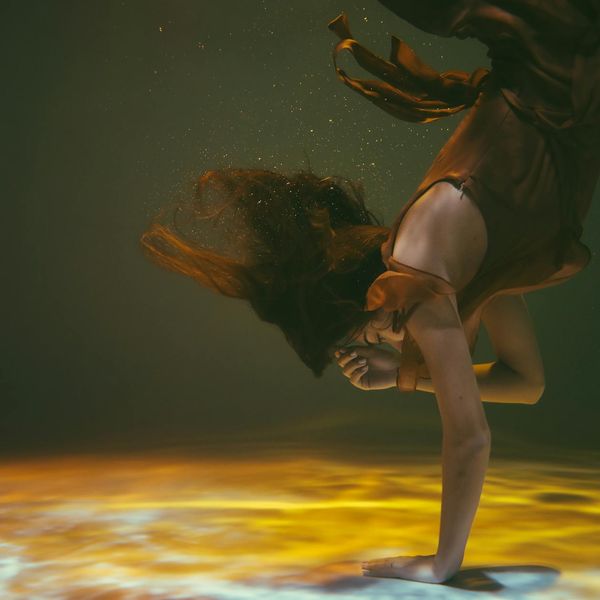 Woman performing a graceful yoga flow, surrounded by soft lighting.